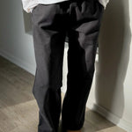 Person wearing a white shirt and dark pants standing on a wooden floor.