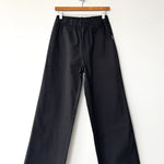 Black pants hanging on a wooden hanger against a white background