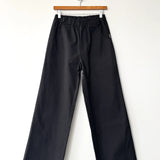 Black pants hanging on a wooden hanger against a white background