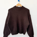 Brown sweater on a wooden hanger against a white background