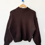 Brown sweater on a wooden hanger against a white background