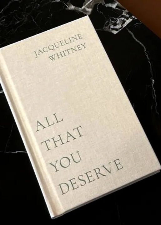 A book titled 'All That You Deserve' by Thought Catalog resting on a marble surface.