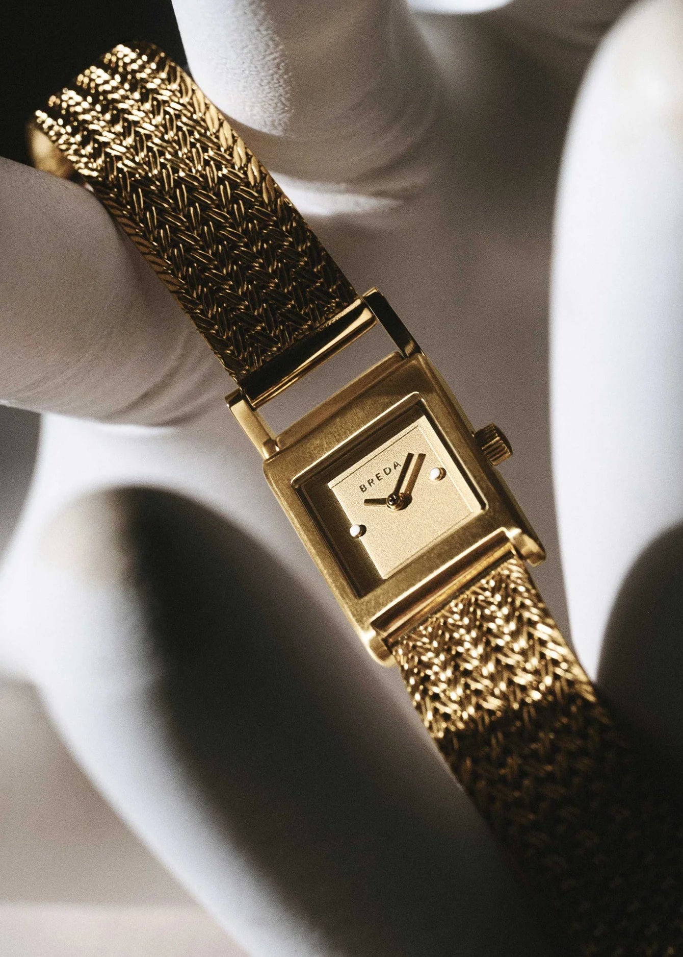 Gold watch with textured strap on a white background