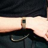 Gold watch on a wrist with a dark background