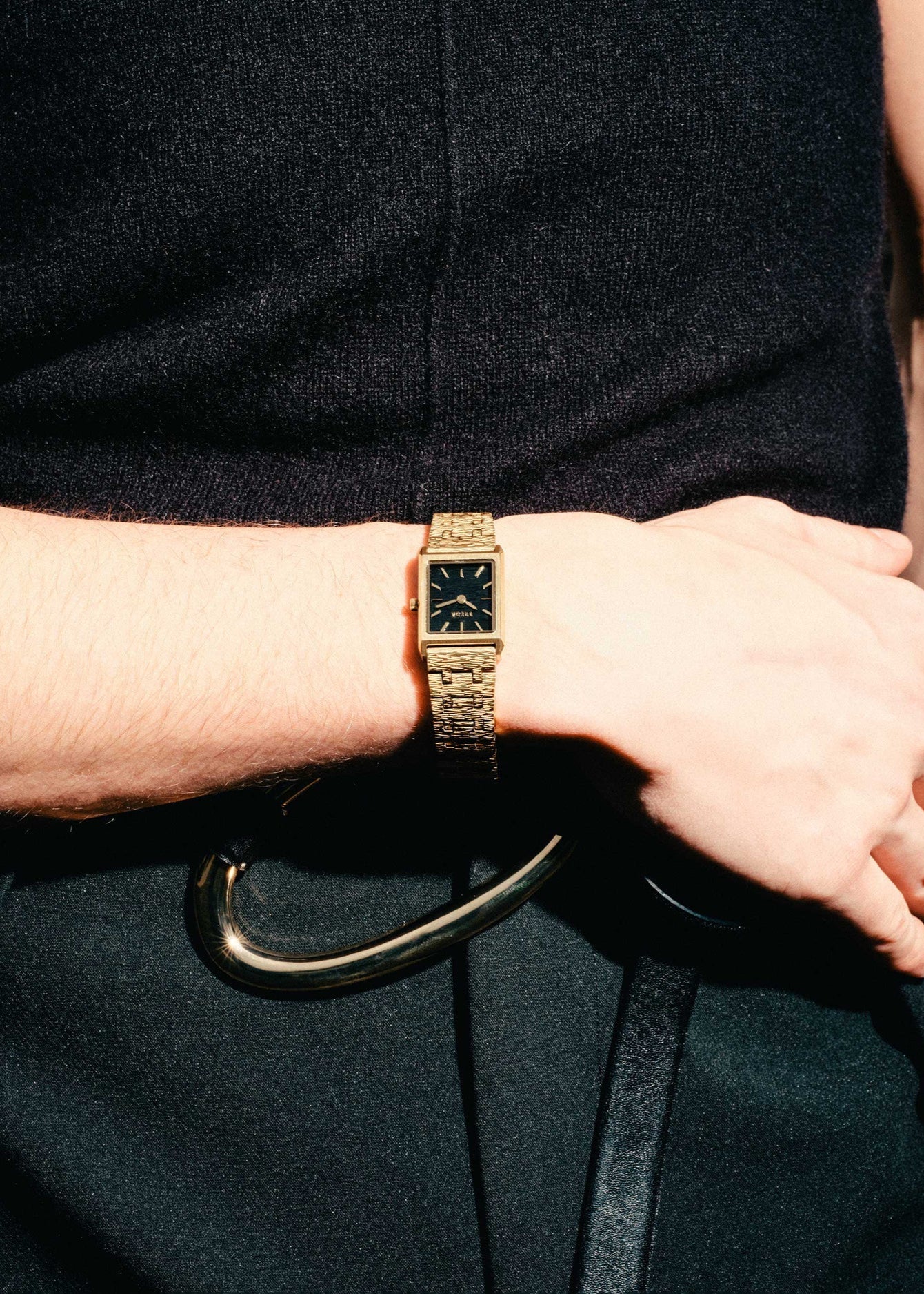 Gold watch on a wrist with a dark background