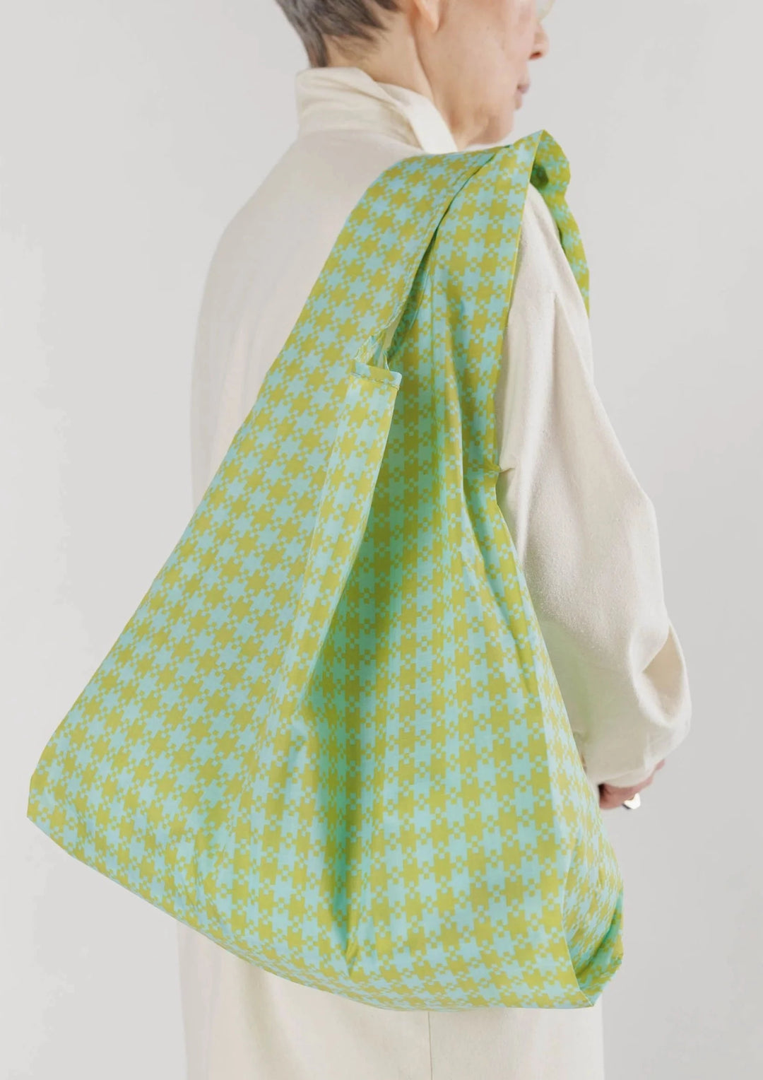 Model holding green checkered reusable bag