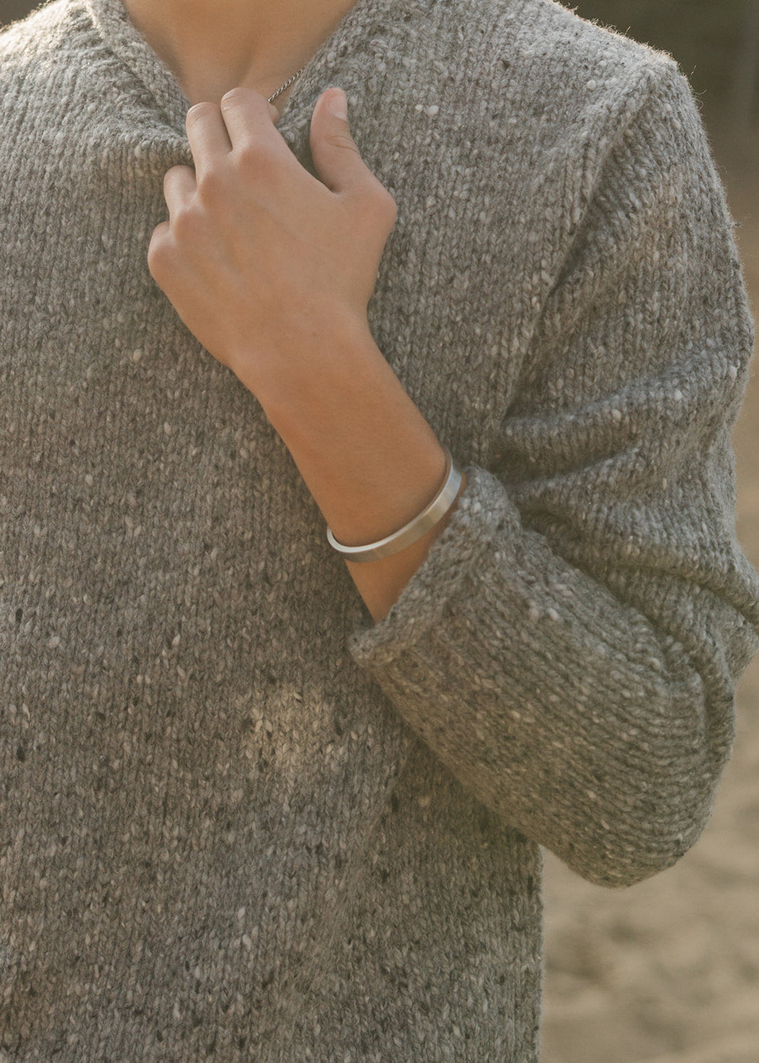 Person wearing a textured sweater with a blurred background
