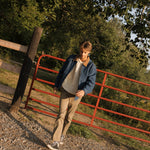Man standing near a red metal gate with trees in the background