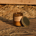 Candle with a label on a wooden surface with hay