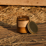 Candle with a label on a wooden surface with hay