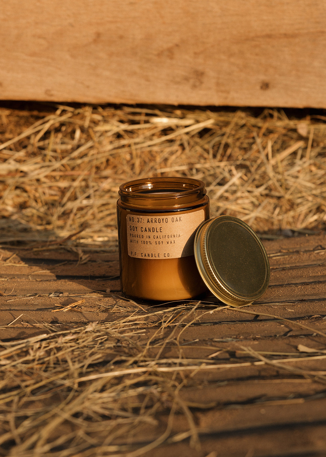 Candle with a label on a wooden surface with hay