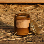 Spiced pumpkin candle in a jar with a label on straw and wooden background