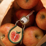 Keychain with apple design on a paper bag filled with apples