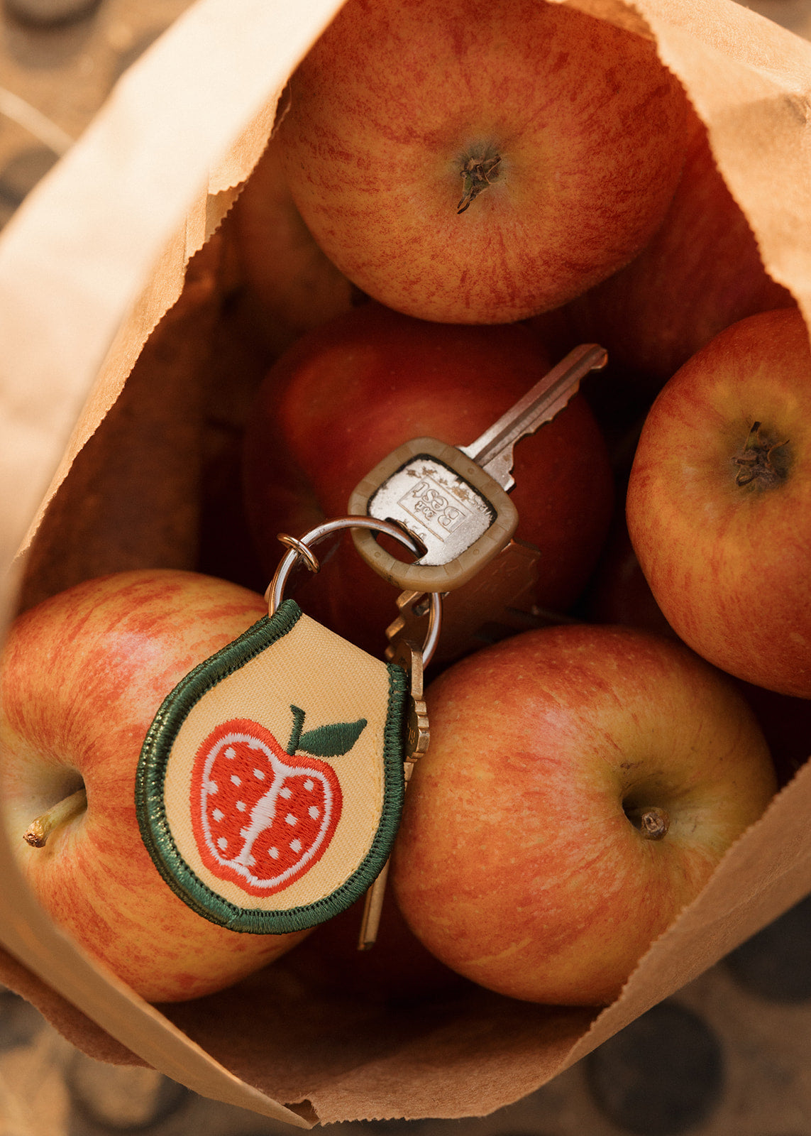 Keychain with apple design on a paper bag filled with apples