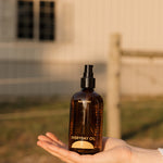 Hand holding a bottle of 'Everyday Oil' by Mauvejay outdoors.