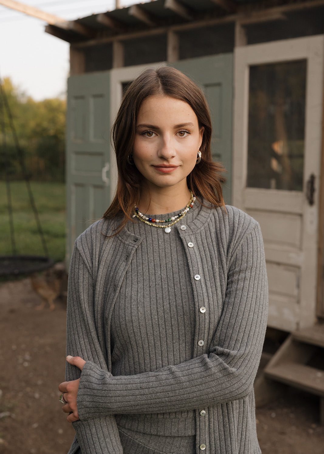 Woman wearing a gray cardigan in front of a green building