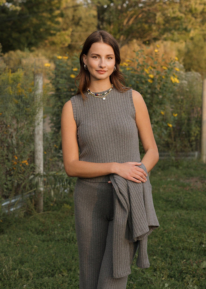 Woman standing in a garden with greenery and a fence in the background