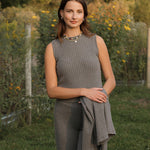 Woman standing in a garden with greenery and a fence in the background