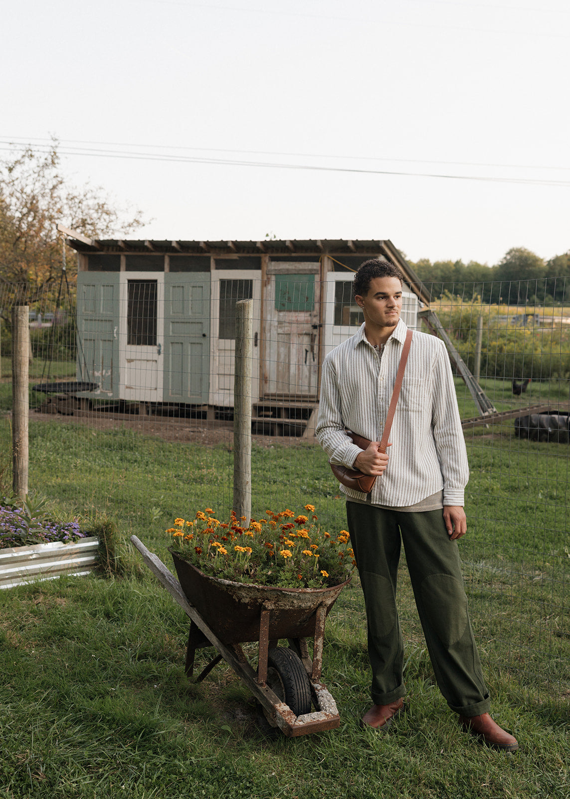 Man standing next to a wheelbarrow with flowers in a garden setting