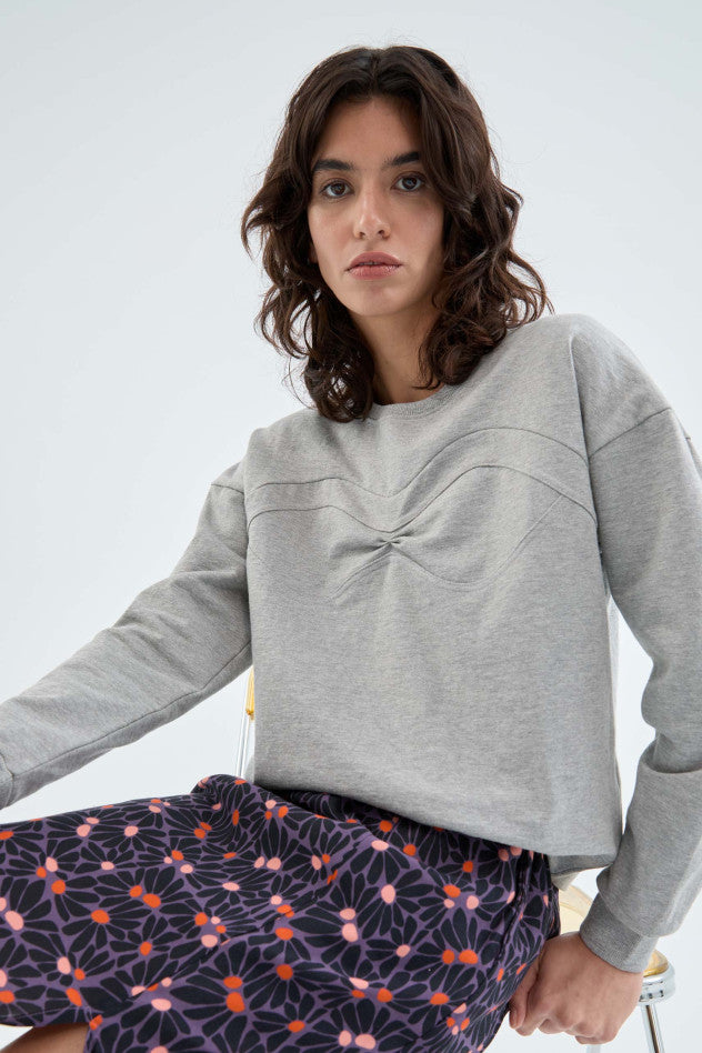 A medium close image of a female model sitting on a stool while wearing the Sweatshirt with Seam Detail 