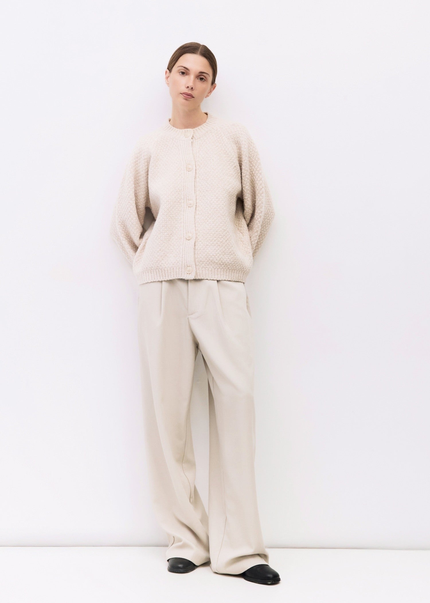 Person wearing a beige outfit on a white background