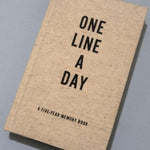 One Line a Day journal laying on grey background.