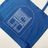Women model holding a denim tote with a sketch of the Frances Jaye store front on it.