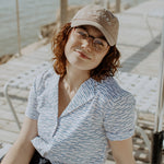 Female model wearing shorts, a short sleeve shirt and tan hat embroidered with Holland