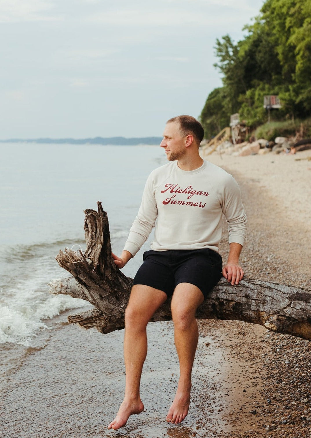 Male model wearing a cream crewneck sweatshirt with Michigan Summers screen-printed on it.