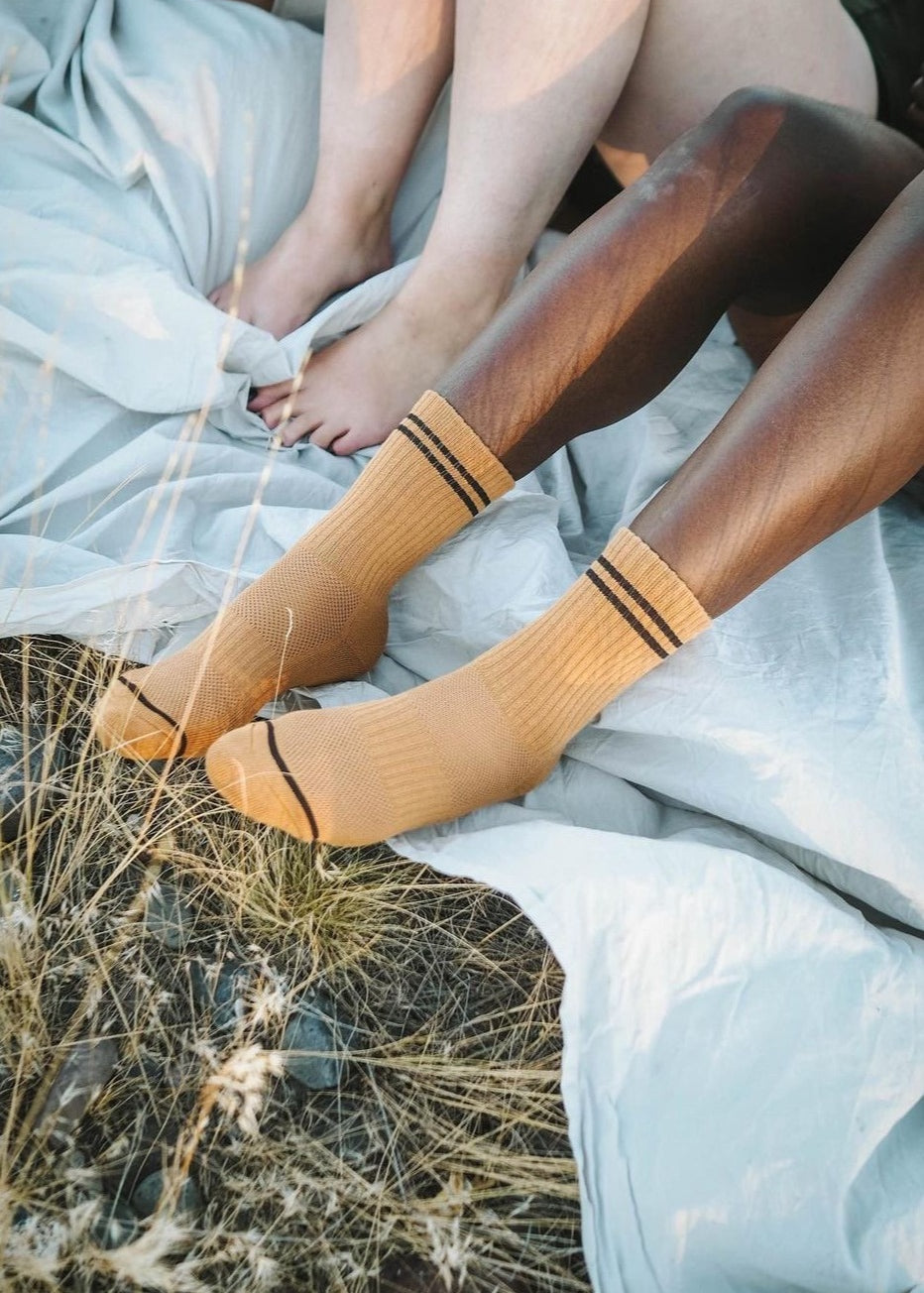 A pair of socks worn by a person sitting, with the socks' color and pattern visible.