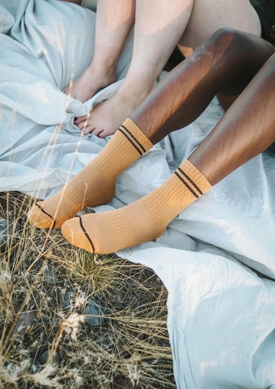A pair of socks worn by a person sitting, with the socks' color and pattern visible.