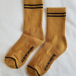 Gold colored socks with navy stripes on a white background.