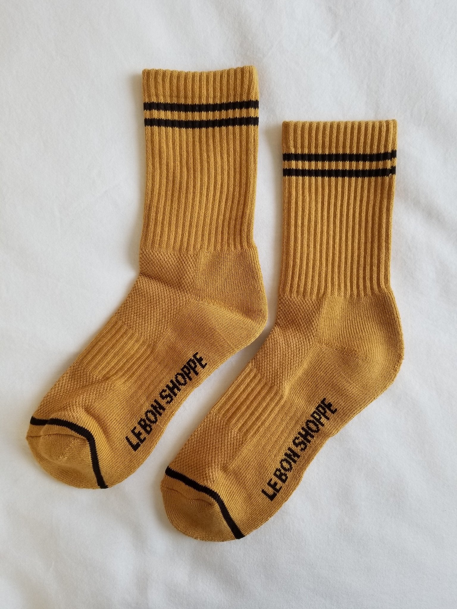 Gold colored socks with navy stripes on a white background.