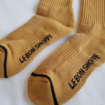 Close up of gold colored socks with navy stripes on a white background.