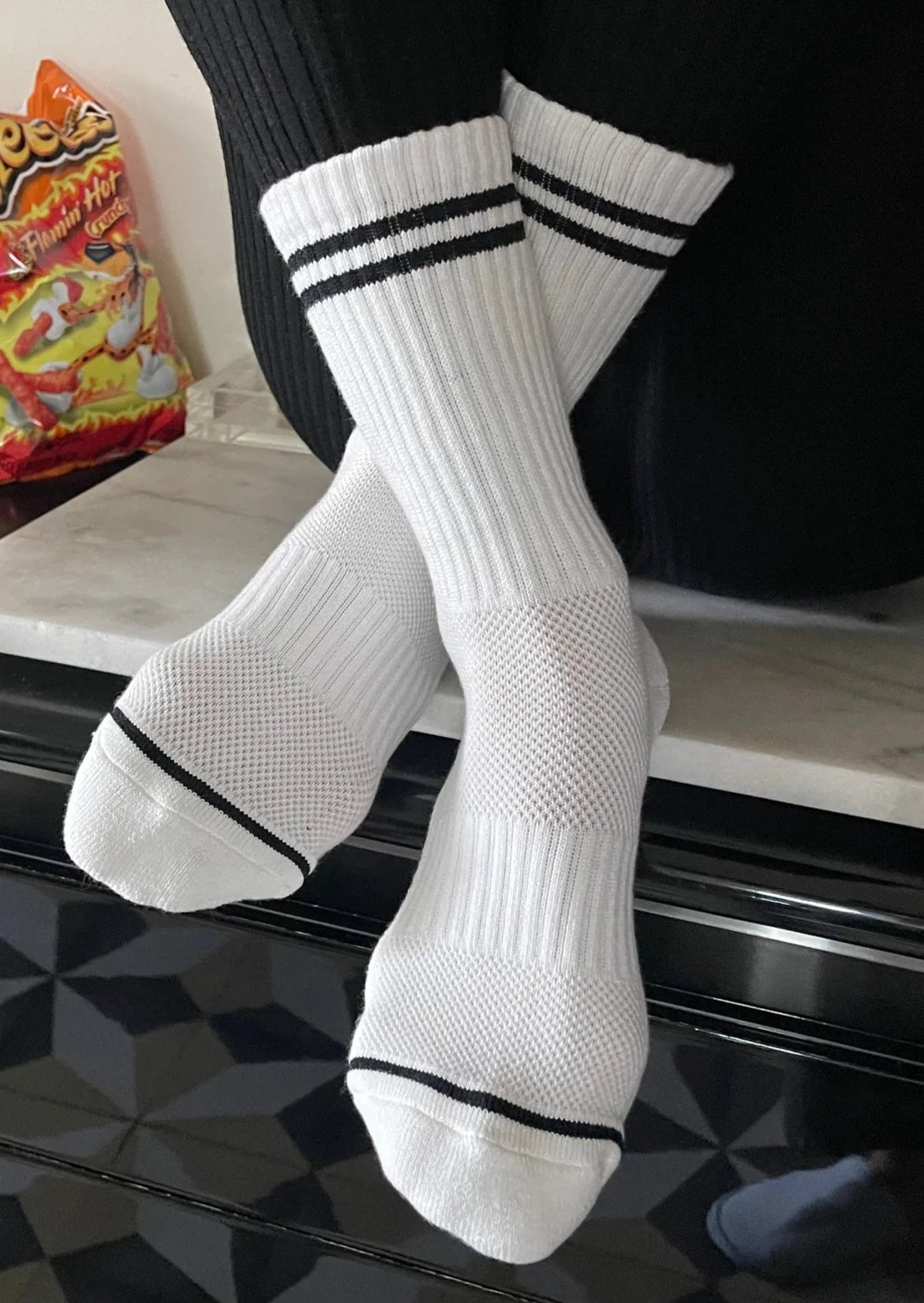 A pair of white socks with black double stripes on the cuffs, displayed on a surface.