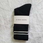 Black socks with white stripes in white Le Bon Shoppe packaging on white surface.