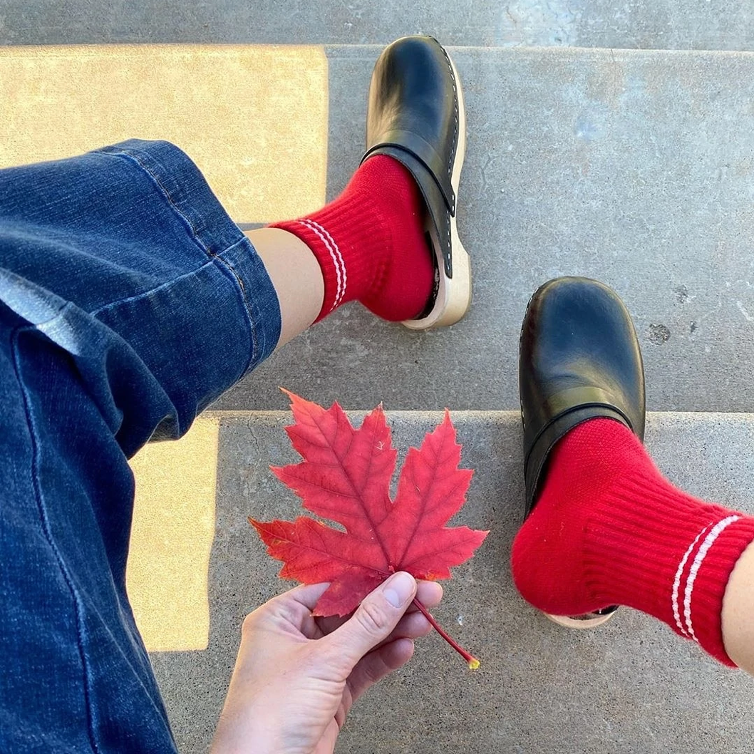 Red socks worn with jeans and black clogs and holing a red maple leaf