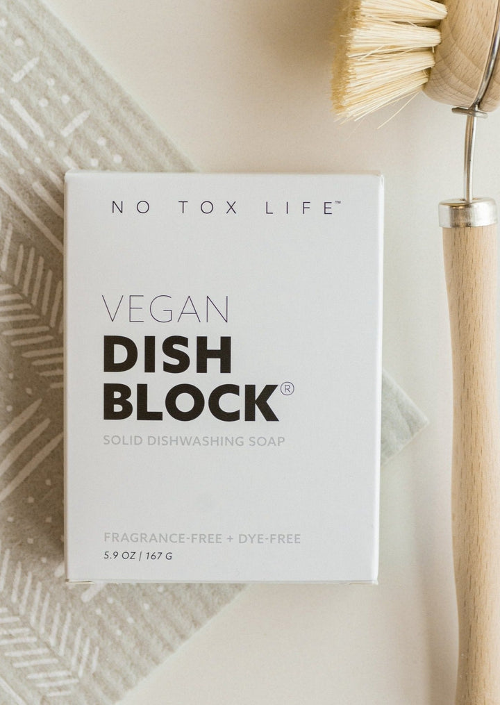 Vegan Dish Block laying on a table with a dish brush.