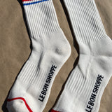 White socks with blue and red socks and e Bon Shoppe branding laying on kraft paper