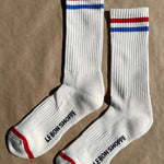 White socks with blue and red socks and e Bon Shoppe branding laying on kraft paper