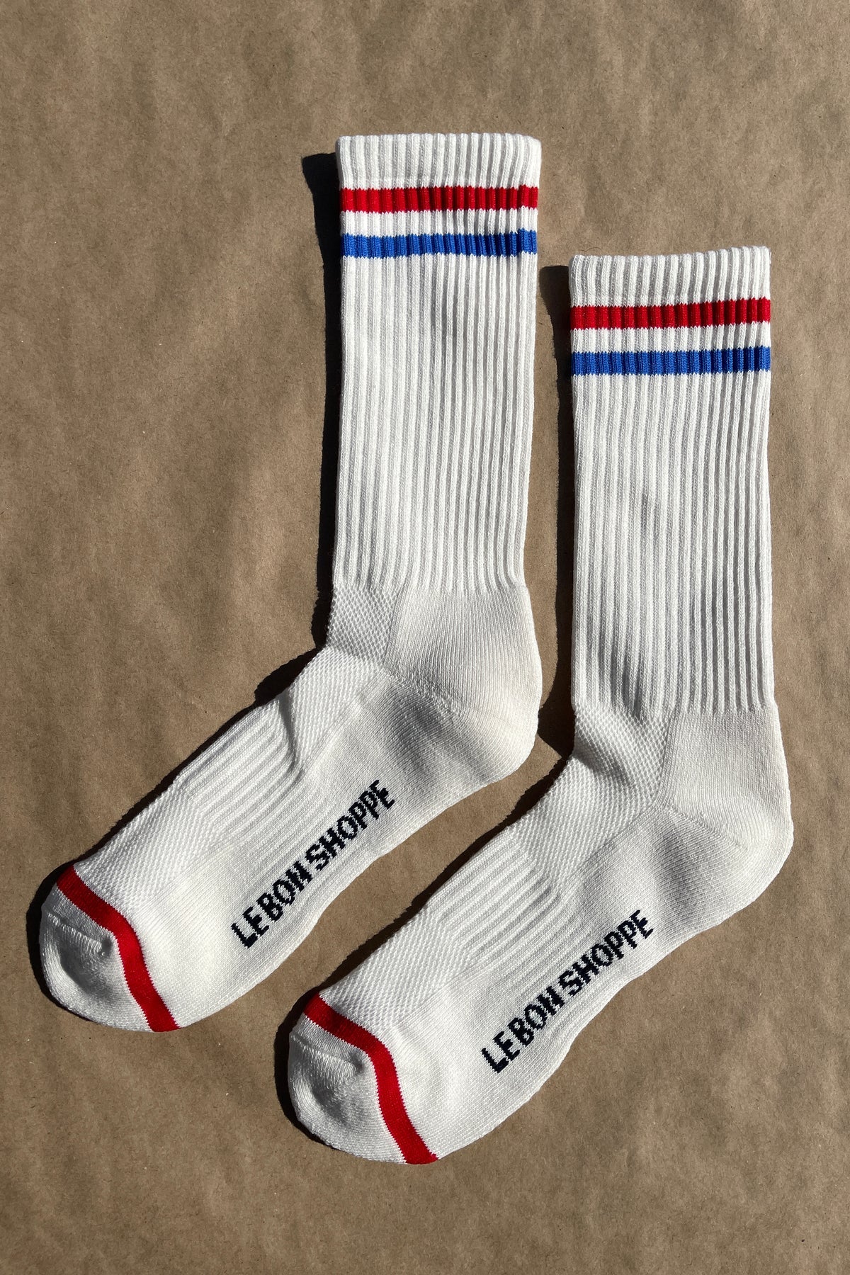 White socks with blue and red socks and e Bon Shoppe branding laying on kraft paper