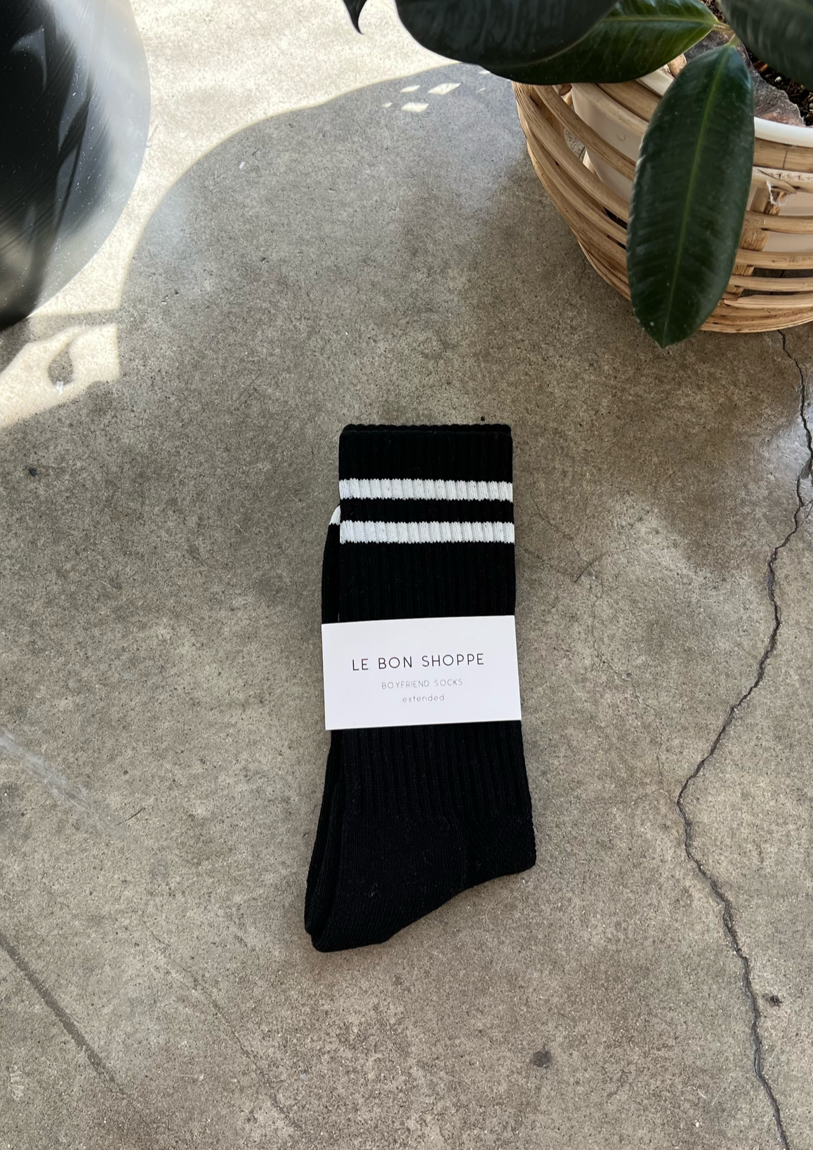 Black socks with white stripes in white packaging on concrete floor