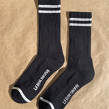 Black socks with white stripes and Le Bon Shoppe branding on kraft paper background