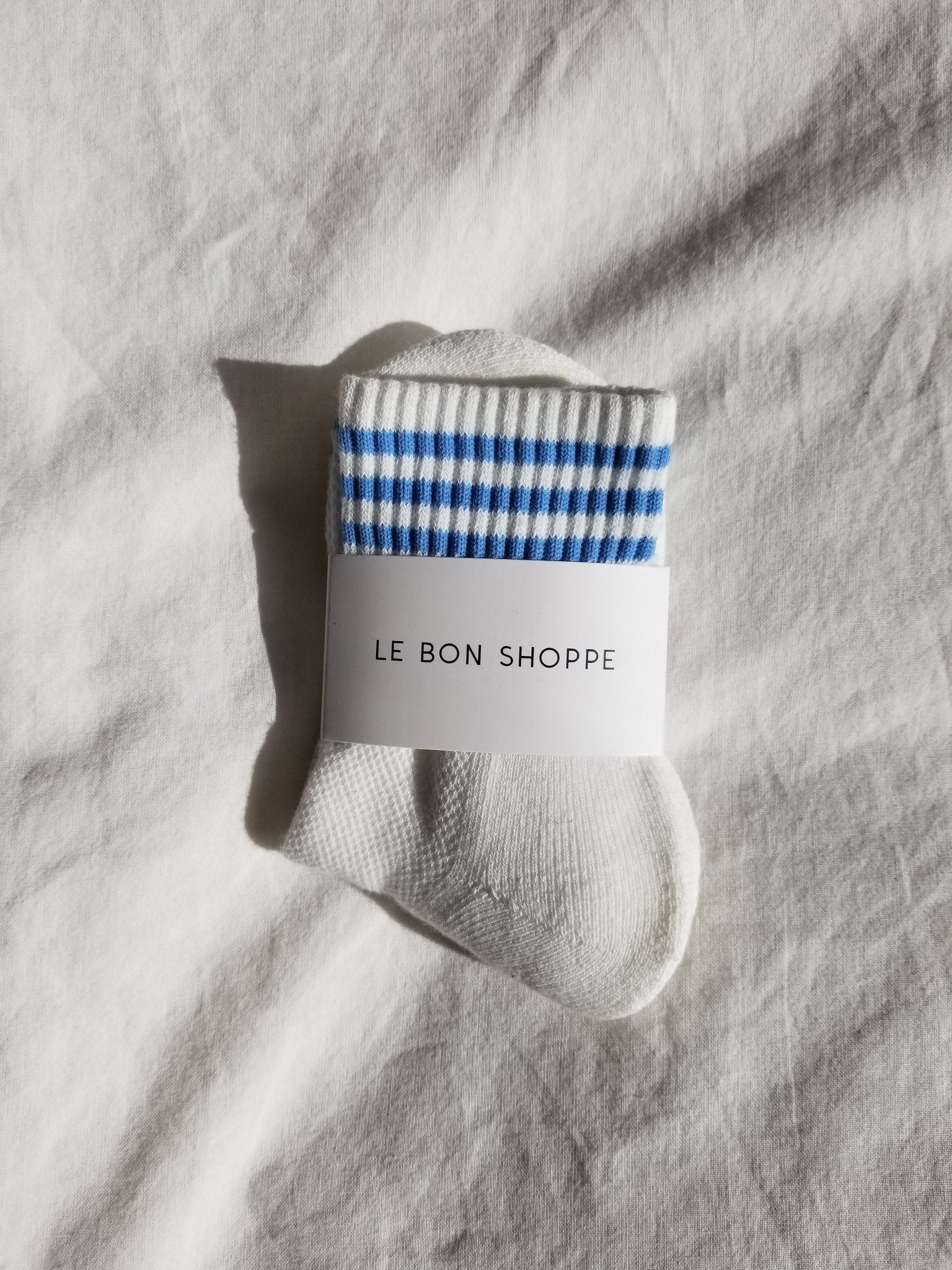 White socks with blue stripes in white Le Bon Shoppe packaging on white background