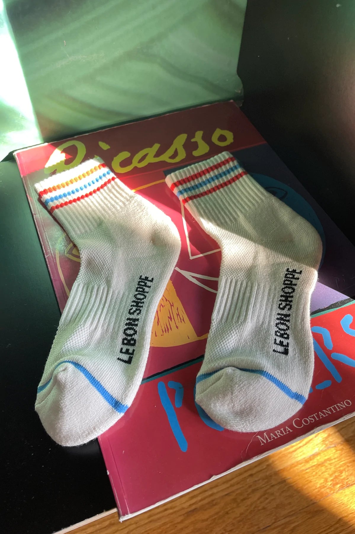 White socks with red and blue stripes laying on Picasso poster