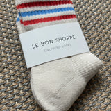 White Le Bon Shoppe socks with red and blue stripes laying on textured carpet