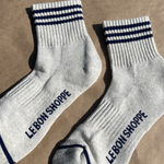 Oatmeal socks with navy stripes and Le Bon Shoppe branding on kraft paper background
