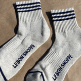 Oatmeal socks with navy stripes and Le Bon Shoppe branding on kraft paper background