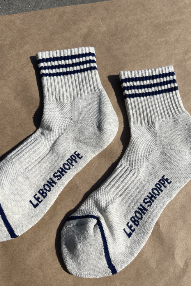 Oatmeal socks with navy stripes and Le Bon Shoppe branding on kraft paper background