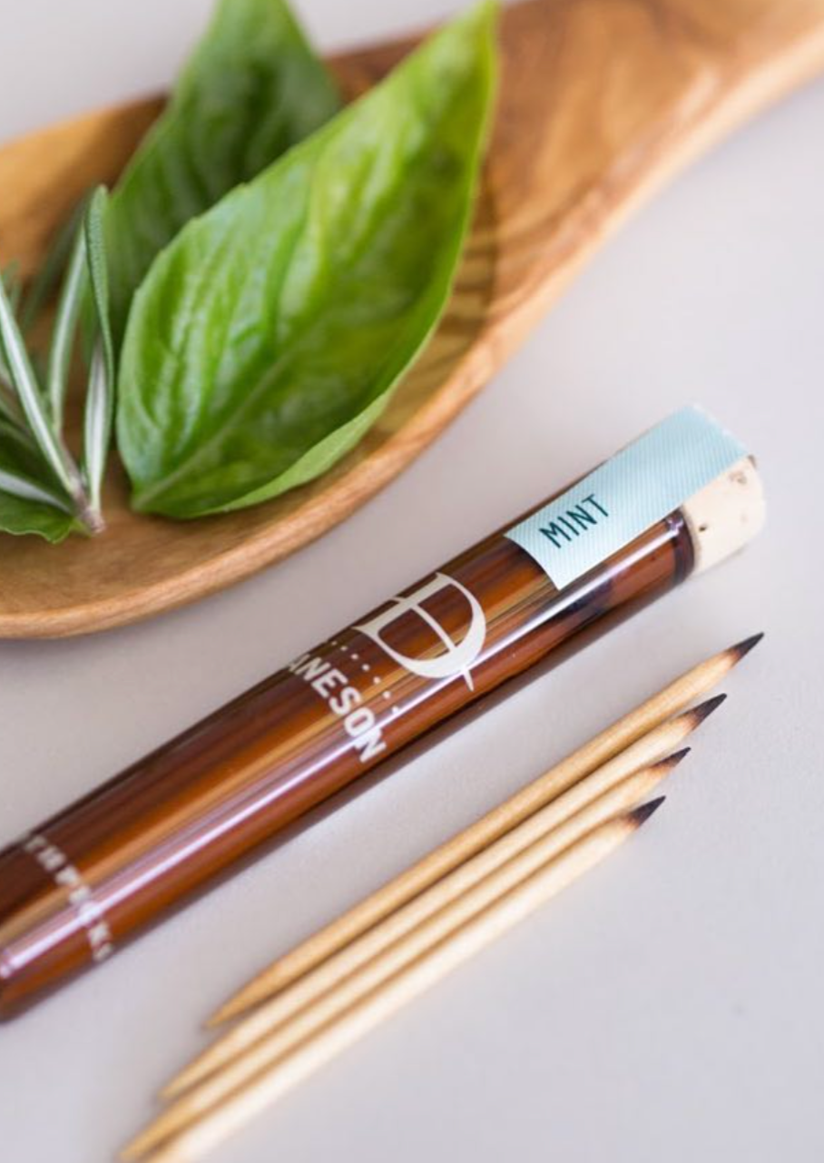 Glass bottle with toothpicks and mint leaves.